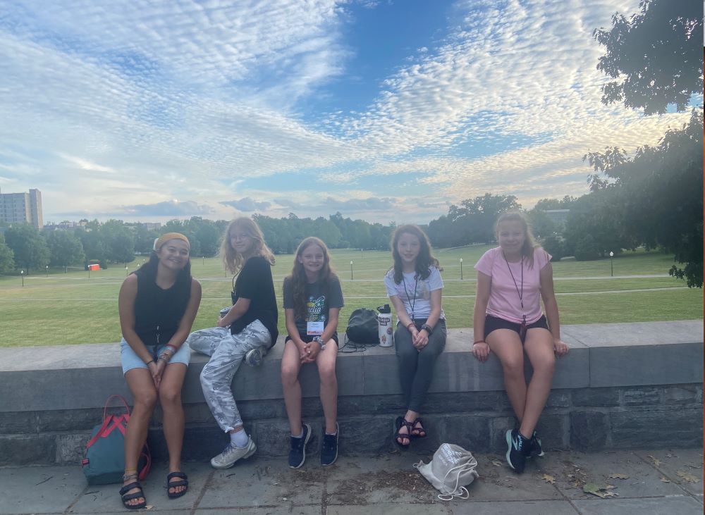 Counselor and students posing in front of a beautiful cloud pattern in the sky